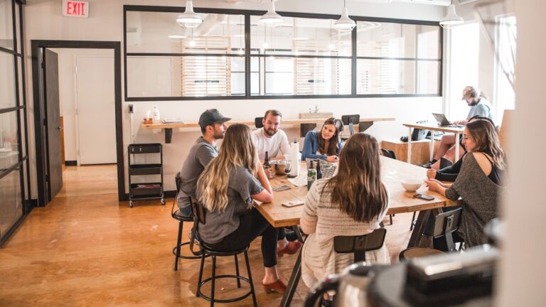 Office setting with a team gathered around a table, engaged in a discussion about telephony software applications.